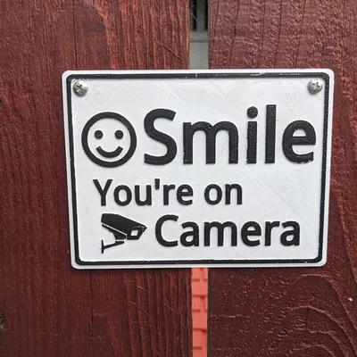 Biển báo "Cười lên, bạn đang ở trên camera" với lỗ vít